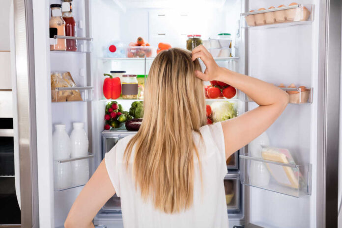 Rear,View,Of,Young,Woman,Looking,In,Fridge,At,Kitchen