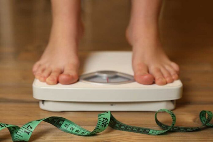 Overweight,Girl,Using,Scales,Near,Measuring,Tape,On,Wooden,Floor,